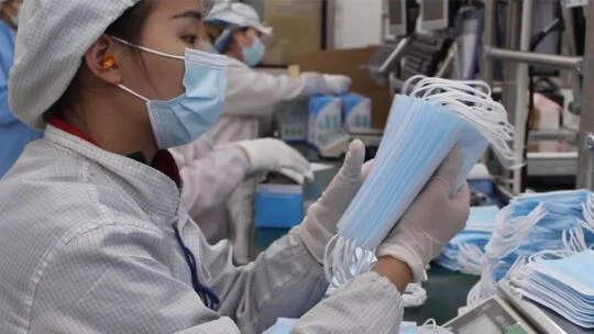 gente en una fábrica haciendo máscaras