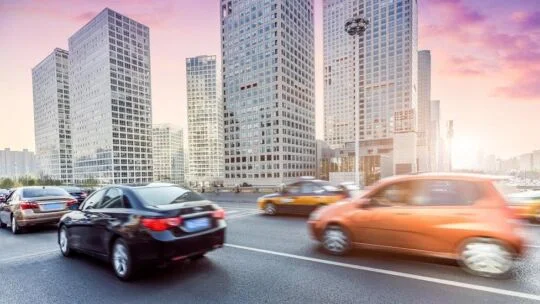 Coches circulando por una calle de la ciudad durante el amanecer.