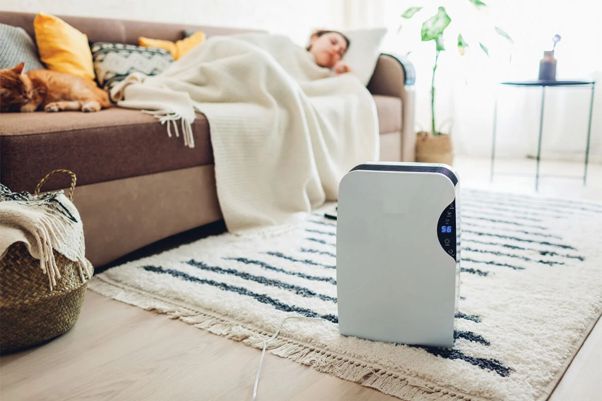 Person, die auf der Couch schläft, während auf dem Boden ein Gerät läuft