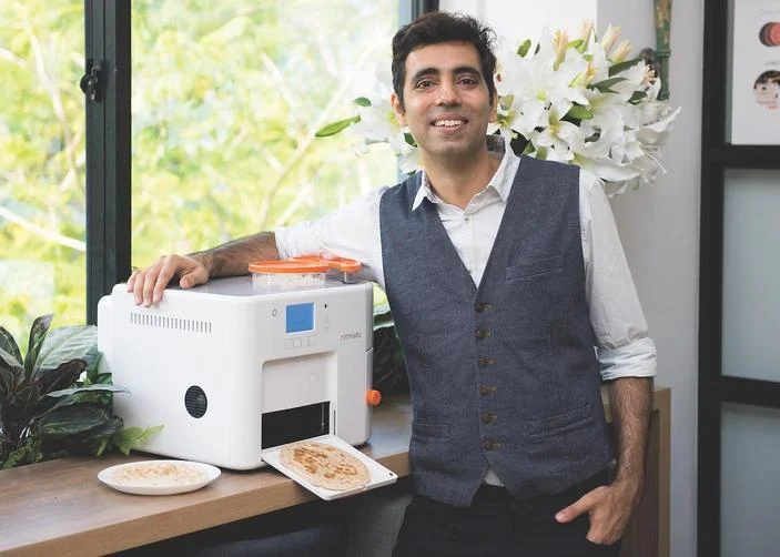 Rishi Israni steht neben seiner Rotimatic Roti-Herstellungsmaschine