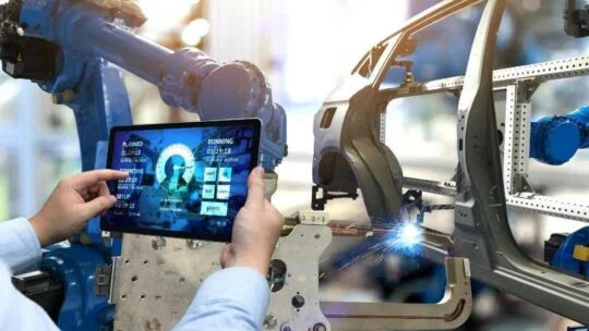 profesional de fábrica que utiliza un dispositivo electrónico portátil para interactuar con equipos de fábrica autónomos
