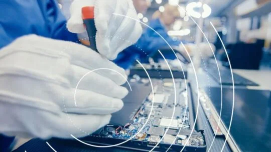 Mano enguantada trabajando en un complejo componente electrónico como parte de un ecosistema de economía circular.